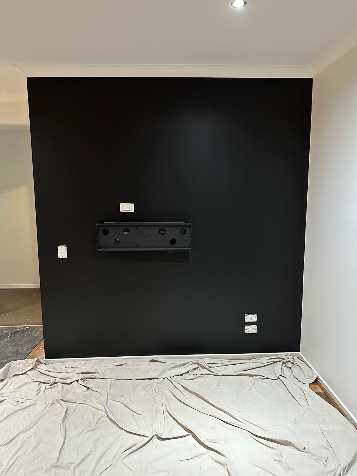 Matte black cinema feature wall with sharp white cornice and skirting lines
