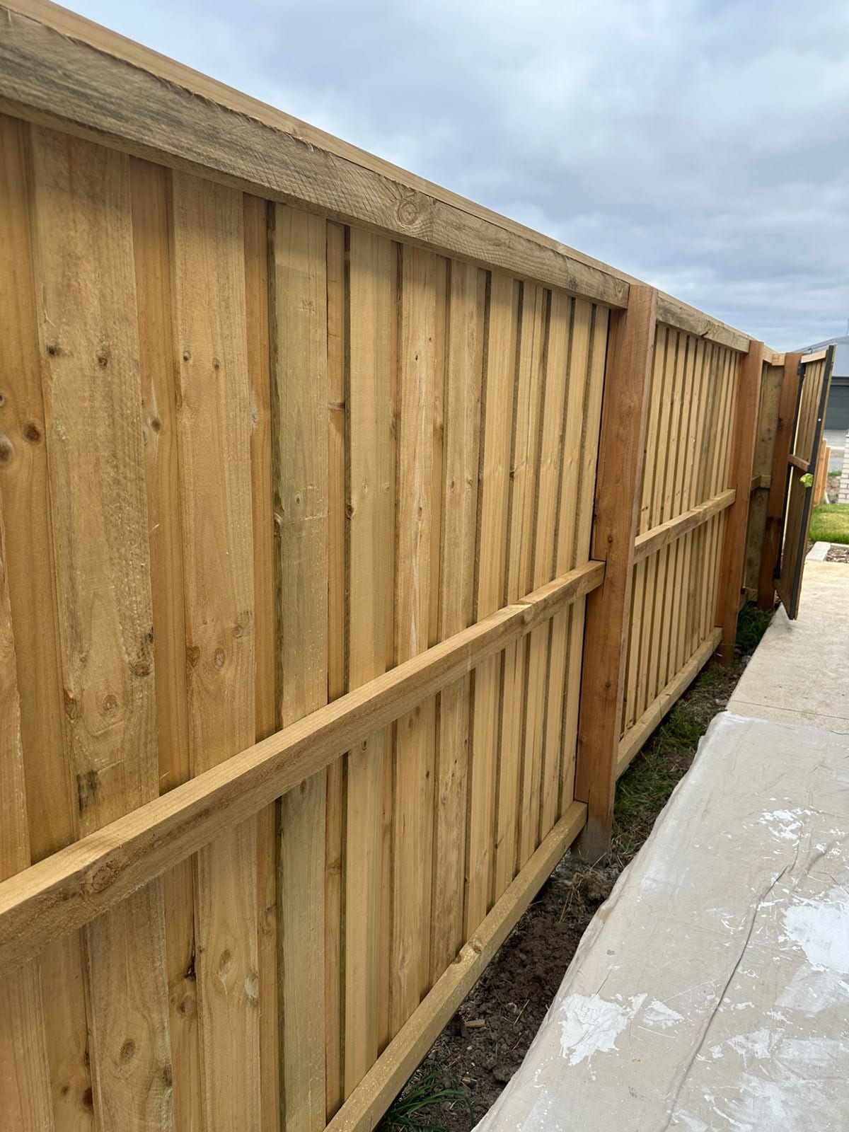 Aged grey timber boundary fence before spray painting