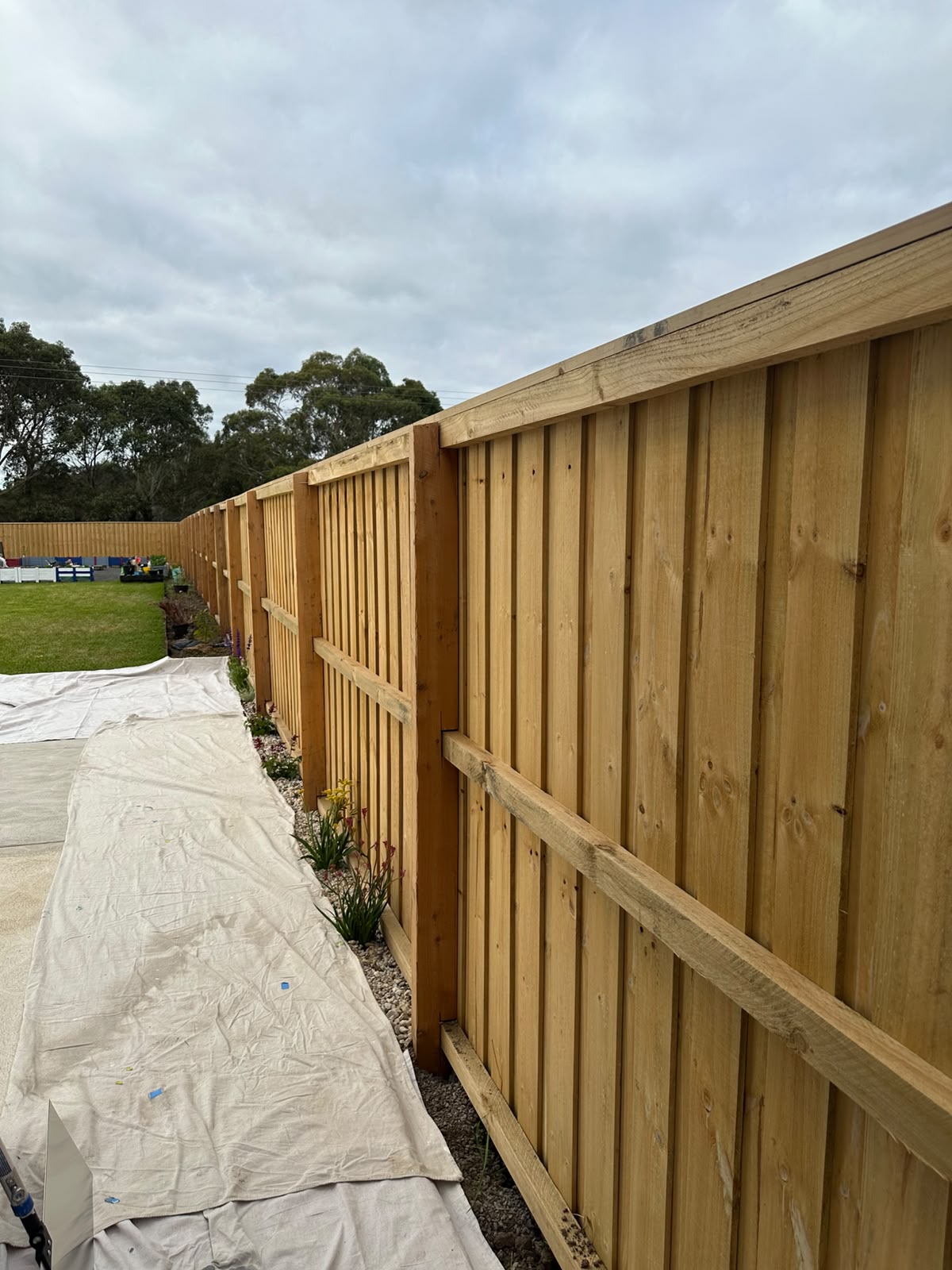Perimeter fence line cleared and ground drop-sheeted before painting