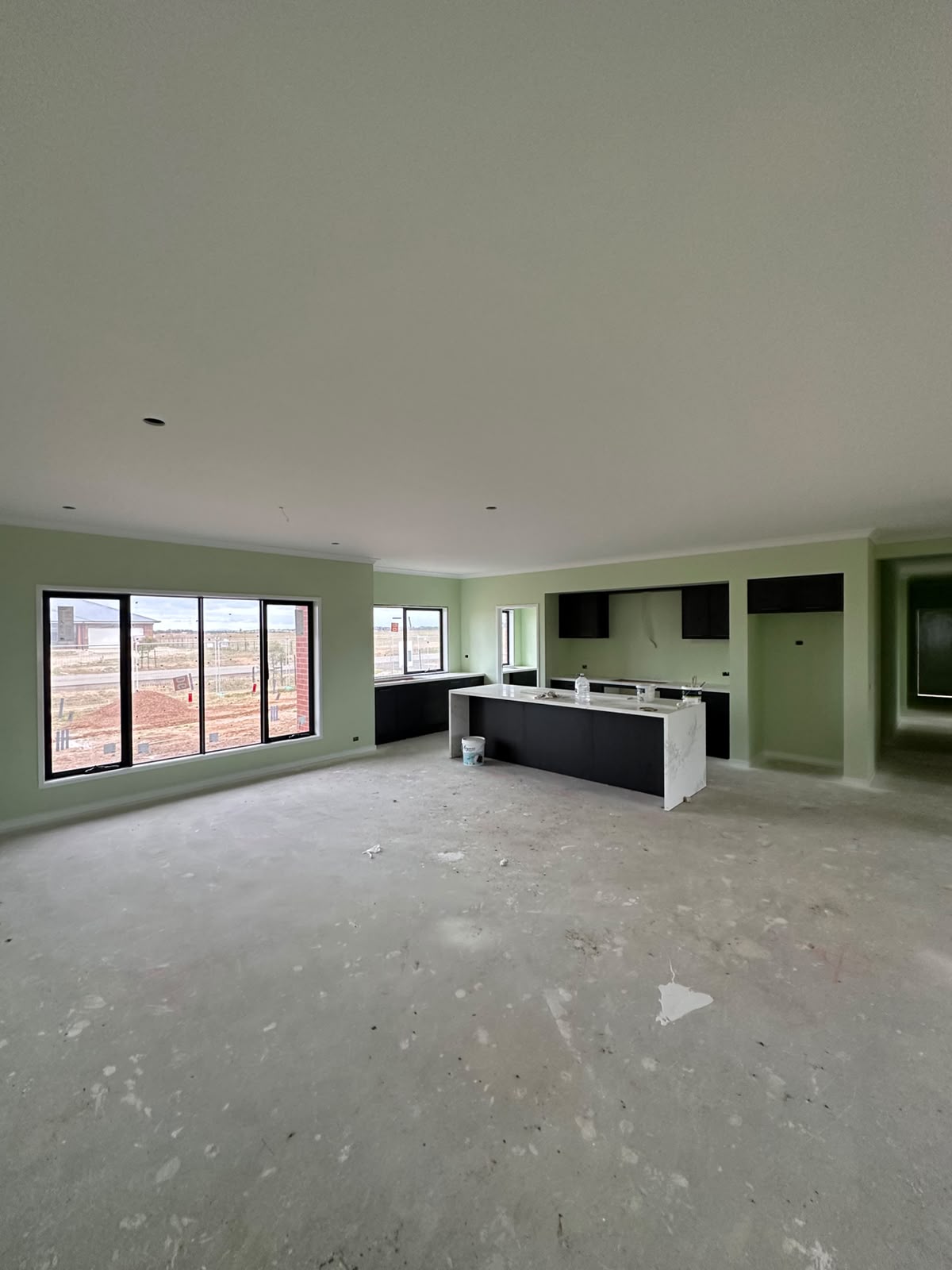 Open plan living and kitchen area painted in soft sage green